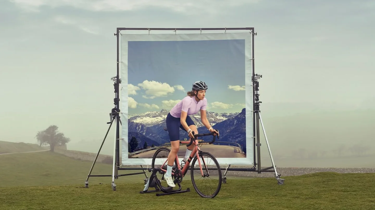 Cyclist riding out of a printed backdrop standing in a field, representing CGI, animation and motion at Growth Yogi